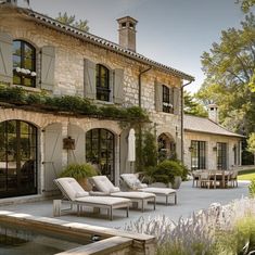 an outdoor patio area with chaise lounges and tables in front of a house