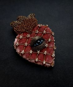 a heart shaped brooch sitting on top of a black surface