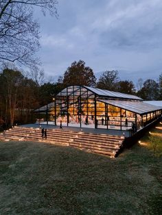 a large glass building with steps leading up to it's roof and stairs in the grass