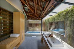 a bathroom with two sinks and a bathtub next to a wooden wall covered in bamboo