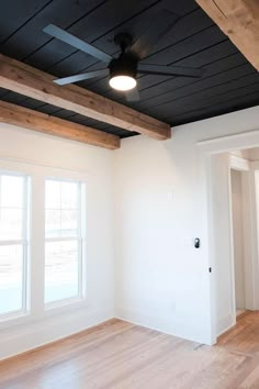 an empty room with wood flooring and ceiling fan in the middle of the room