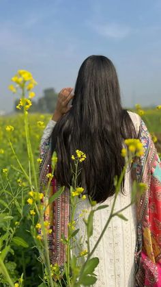 the back of a woman's head standing in a field of yellow wildflowers