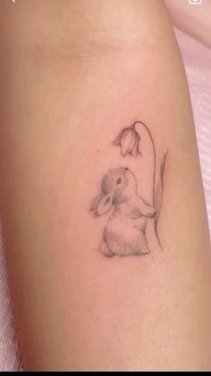 a small bunny tattoo on the thigh with a flower in it's left arm