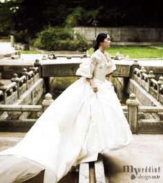 a woman in a white dress is standing on some concrete steps and looking off into the distance