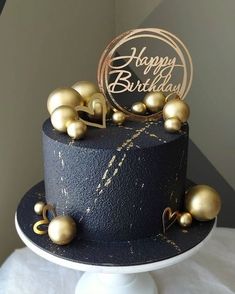 a black and gold birthday cake with decorations