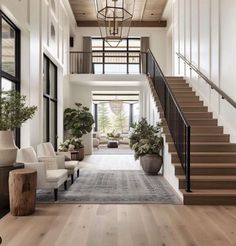 a living room filled with lots of furniture next to a stair case and potted plants