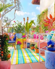 a balcony with potted plants and colorful rugs