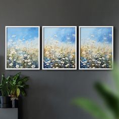 three paintings hanging on the wall next to a potted plant