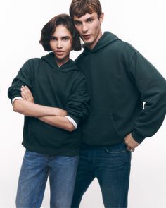 two people standing next to each other with their arms crossed