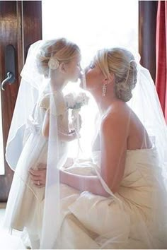 two brides kissing each other in front of a window