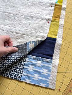 someone is cutting fabric on top of a piece of quilting material with scissors and tape