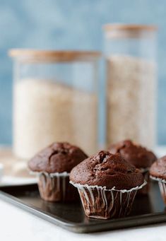 several chocolate muffins on a plate next to salt and pepper shakers