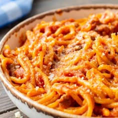 a white bowl filled with spaghetti on top of a wooden table