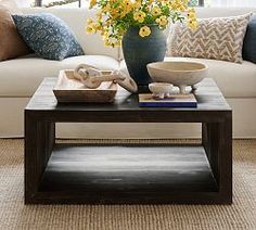 a living room with white couches and yellow flowers in a vase on the coffee table