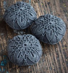 three gray knitted balls sitting on top of a wooden table