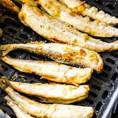 some fish are cooking on a grill with seasoning sprinkled around it's edges