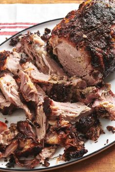 a white plate topped with sliced meat on top of a wooden table