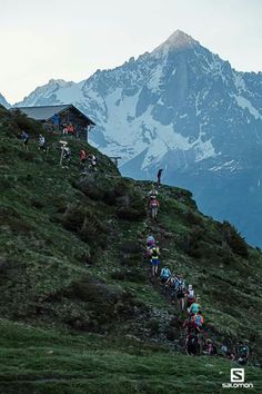 a group of mountain bikers climbing up a grassy hill with mountains in the background