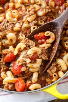 a pot full of pasta and meat with a wooden ladle in it, ready to be eaten