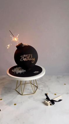 a black and white birthday cake with sparklers on it sitting on a marble table