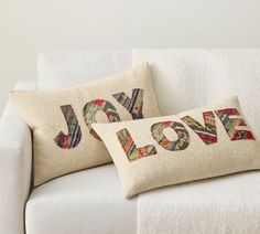 two pillows that say joy and love on the back of a white couch in a living room