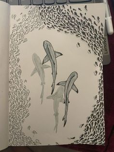 an open notebook with two dolphins in the water and corals around it on top of a computer keyboard