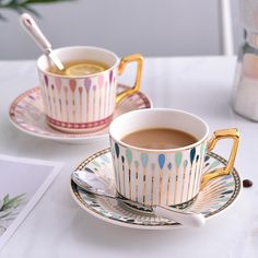 two cups of coffee sitting on top of a saucer next to a cup filled with liquid