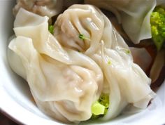 dumplings and broccoli are in a white bowl