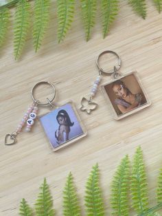 two key chains with pictures on them sitting next to ferns