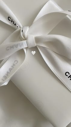 a white present wrapped in satin ribbon with the word charm on it's side