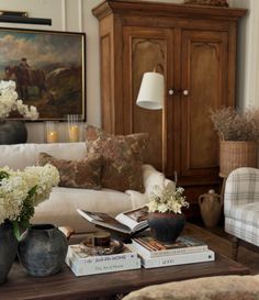 a living room filled with furniture and flowers in vases on top of bookshelves