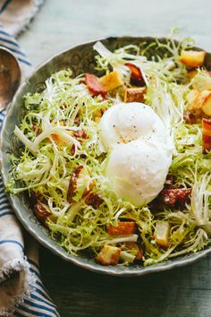 a bowl filled with lettuce and eggs on top of a blue table cloth