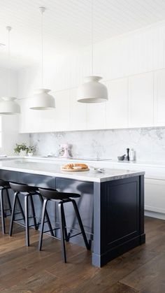 a kitchen with marble counter tops and stools in front of the island that has four black barstools