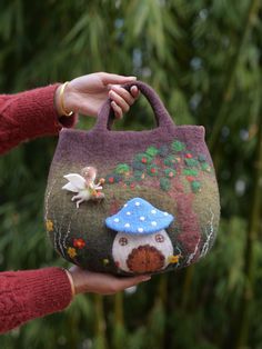 a hand holding a small purse with a mushroom on the front and a bird on the back