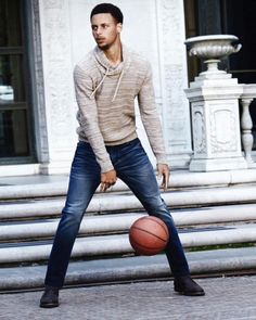 a man holding a basketball standing in front of a building with stairs and steps behind him