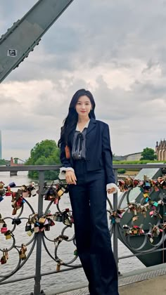 a woman standing next to a bridge with many padlocks on it's sides