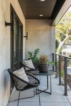 two black chairs sitting on top of a balcony next to a table and potted plant