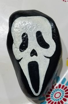 a black and white rock with a ghost face painted on it's front side