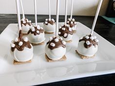 there are many desserts with white and brown icing on the sticks in front of them