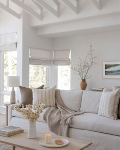 a living room filled with white furniture and lots of pillows on top of the couch