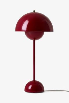 a red table lamp sitting on top of a white floor