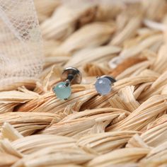 two silver and blue rings sitting on top of a woven basket next to a white bag