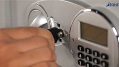 a hand is pressing the button on an electronic keypad that is attached to a wall mounted faucet