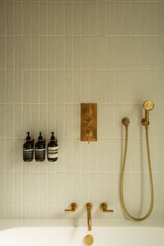 a white bath tub sitting under a faucet next to a wall mounted soap dispenser