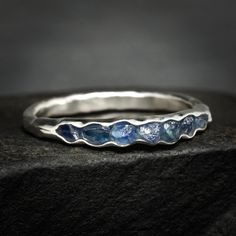 a silver ring with three blue stones on the inside and one white stone in the outside