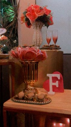 a vase with flowers on top of a table next to some wine glasses and other items