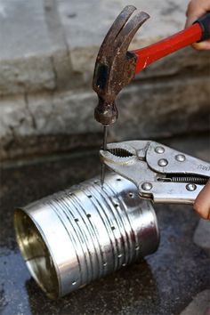 a person using a pair of pliers to open a can with metal parts on it