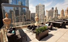 an outdoor seating area on the roof of a building with skyscrapers in the background