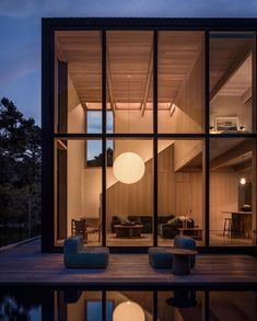 the inside of a house that is lit up at night with large windows and furniture