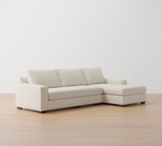 a white couch sitting on top of a hard wood floor next to a white wall